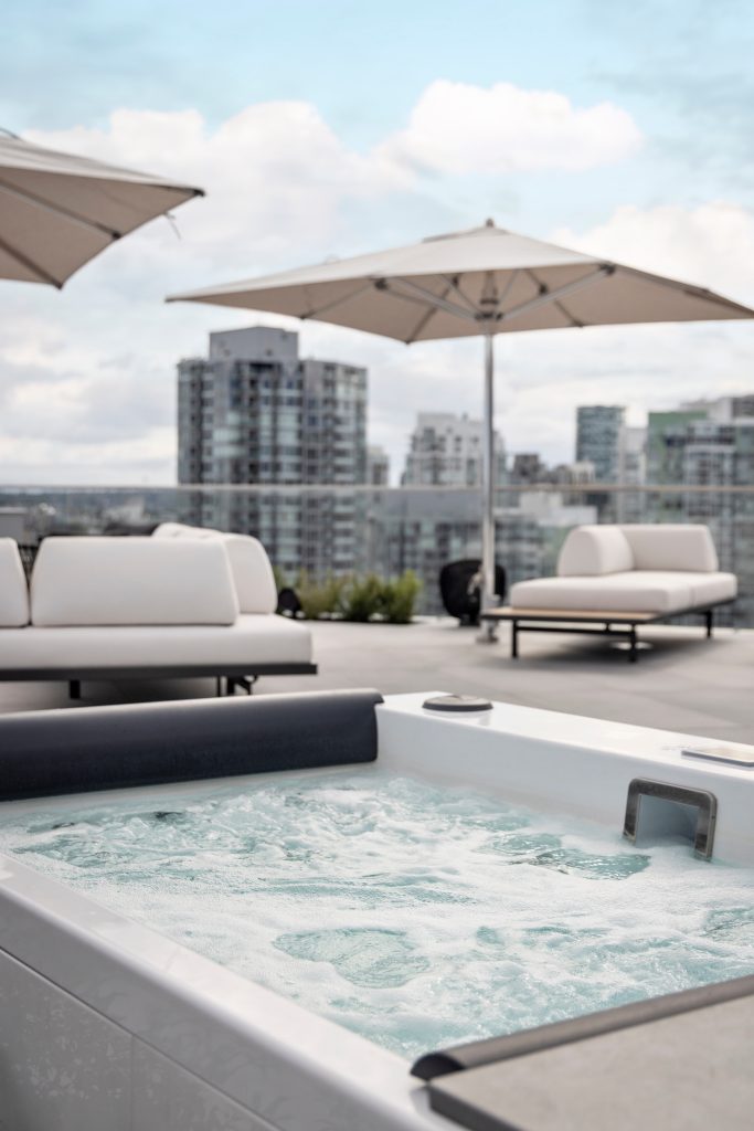 Swicks_918_Cooperage_Web-8-1766 - Swick's Landscaping Ltd. Rooftop pool with white loungers and beige umbrellas overlooking a city skyline