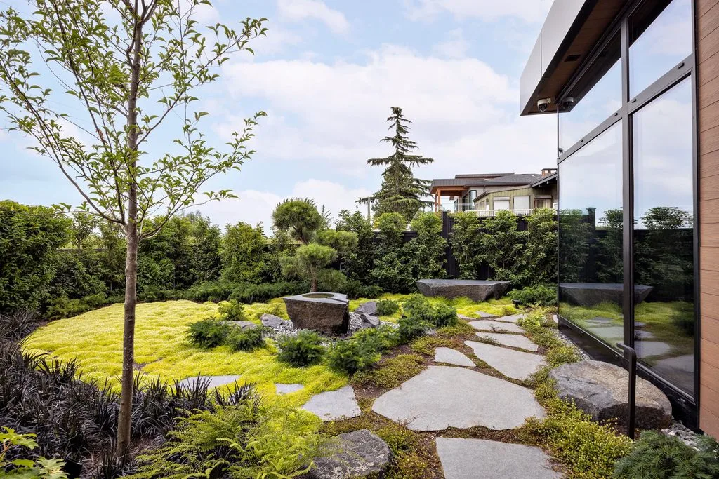 Swicks_4280_River_Web-29-2485 - Swick's Landscaping Ltd. Modern backyard garden with irregular stone stepping path, mossy ground cover, and a glass-walled building on the right.