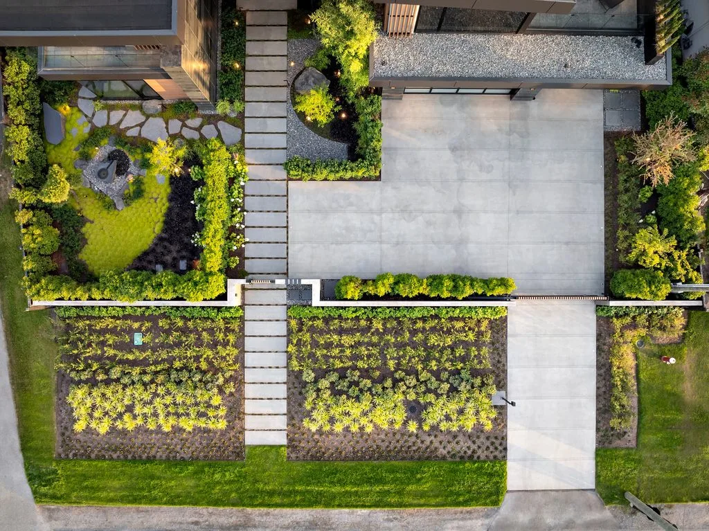Swicks_4280_River_Web-73-0206 - Swick's Landscaping Ltd. Aerial view of a modern house entrance with a stepping-stone path through a landscaped garden and a large concrete driveway.