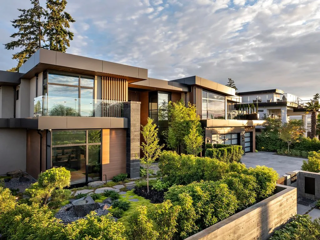 Swicks_4280_River_Web-74-0226 - Swick's Landscaping Ltd. Modern row of contemporary houses with large glass windows, metal panels, and a landscaped front yard under a partly cloudy sky.